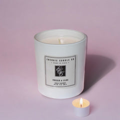 A white candle with a light lilac background